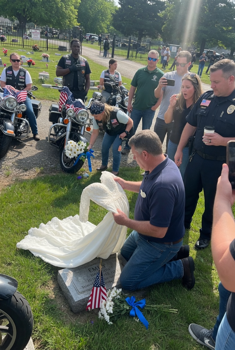 On a clear Saturday morning in Iowa, visitors froze in disbelief when they saw a leather-vested biker sitting in the middle of a cemetery, clutching a white wedding dress to his chest like a man who had completely lost control.
